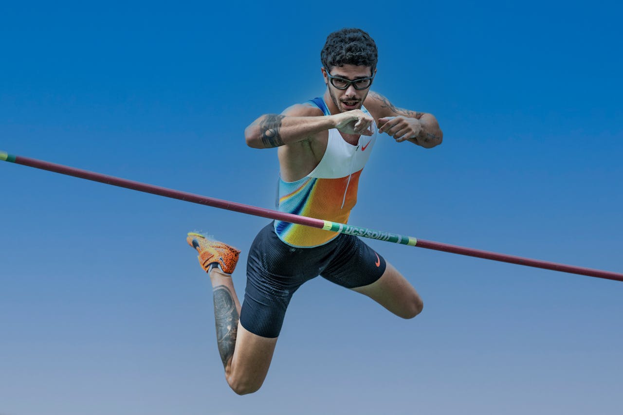 about-bg Athlete performing a pole vault jump, showcasing skill and athleticism against a clear blue sky.
